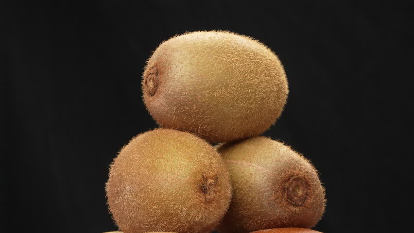 A pile of fresh, whole kiwi fruits spinning 360 degrees. Isolated on a black background. Studio shot for healthy food, Vitamin C, or diet concepts.