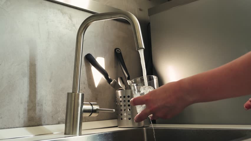 Woman pouring tap water into glass, pure drinking water concept. High quality 4k footage