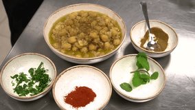 A colorful assortment of spices and garnishes laid out next to a vibrant chickpea dish. The image showcases fresh herbs, paprika, and other spices arranged artistically in small bowls - Powered by Shutterstock - Get 15% off with code: PIKWIZARD15
