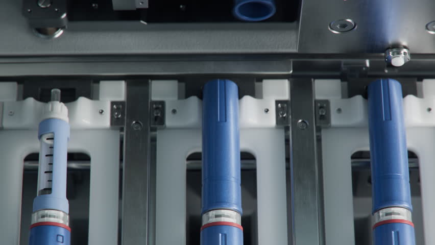 Close-up of Medical Injector Pens on Conveyor Line during Production Process at Modern Pharmaceutical Factory. Weight Loss Medication Manufacturing. Medicinal Drug Production Plant. 