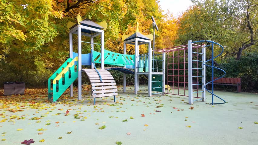Empty children playground under colorful autumn foliage. Great for family, travel, or urban park footage.