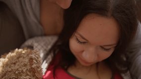 Loving husband and pregnant wife lying together on the couch, smiling while playing with baby shoes on her belly. Warm and emotional family moment. close up mans fingers on woman - Powered by Shutterstock - Get 15% off with code: PIKWIZARD15