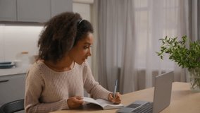African American woman at home writing notes looking laptop listening music in headphones audio sound enjoying song singing noting e-learning girl female student with computer at kitchen happy study - Powered by Shutterstock - Get 15% off with code: PIKWIZARD15
