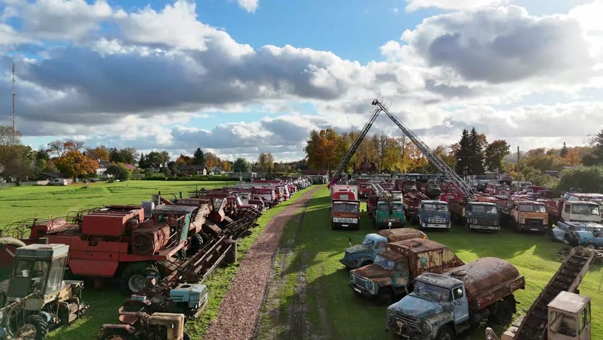 Aerial view of old rusty trucks and machinery in countryside scrapyard on autumn day