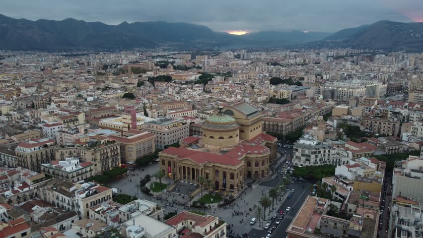 Dramatic 4K drone footage of Teatro Massimo in Palermo, Sicily, captured during a breathtaking sunset. The video highlights the grand neoclassical architecture, warm evening light and vibrant cityscap