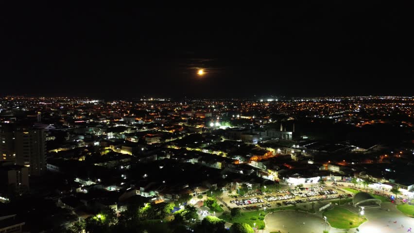 Full moon rising over a city riverside at night with city lights reflecting on dark water in Brazil