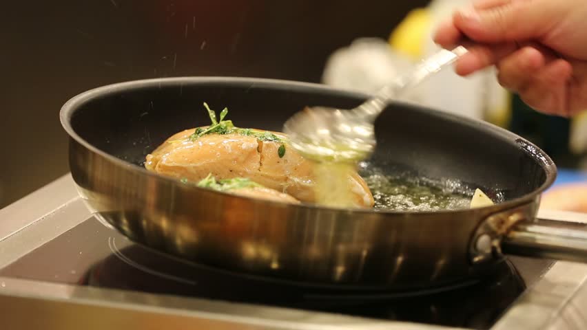 A professional chef is cooking salmon fillet in a pan, it looks appetizing