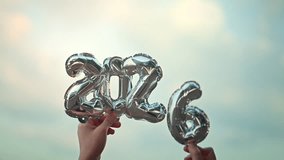 Hands holding silver number balloons forming 2026 with soft sky background, new year celebration and holiday concept for future, happiness, and greeting season - Powered by Shutterstock - Get 15% off with code: PIKWIZARD15