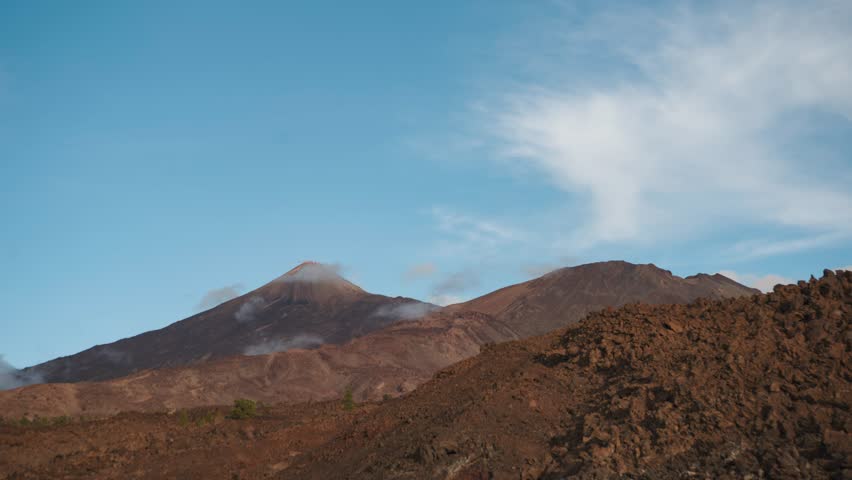 Beautiful 4K time lapse showing clouds flowing around Mount Teide and Pico Viejo volcanoes during a colorful sunset in Teide National Park, Tenerife, Canary Islands