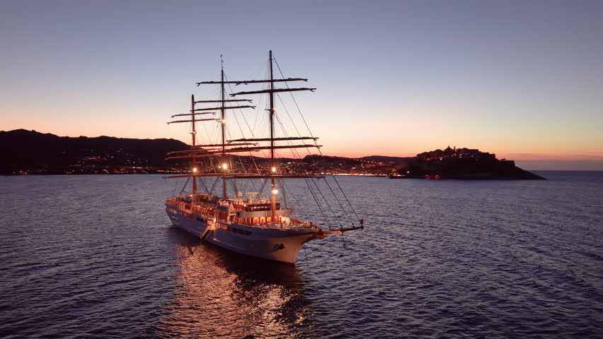 sunset ship glow, tranquil sunset voyage aboard grand threemasted vessel with reflective waters. Calvi. Corsica. France