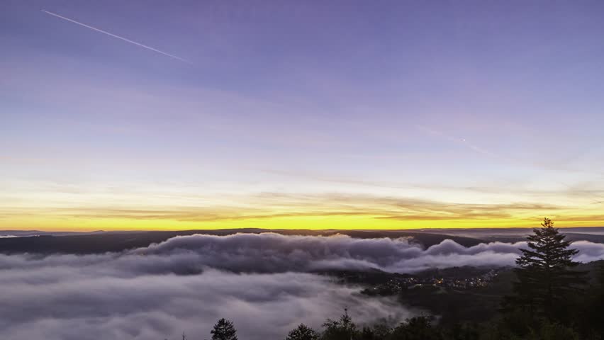 Witness the breathtaking sunrise timelapse at the Rhine River near Bad Salzig, Germany. Clouds blanket the valley as vibrant colors light up the sky, creating a serene morning atmosphere.