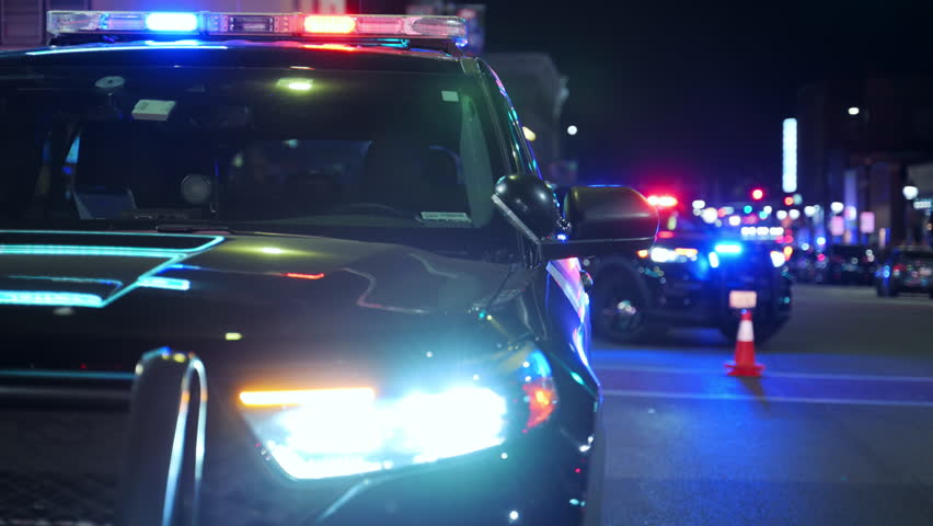Police cars with flashing lights on service at the city street at night. Front view. 