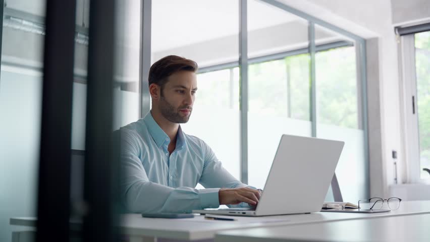 European businessman ceo specialist using computer technology app for work online. Young professional specialist latin hispanic businessman working on laptop pc sitting at desk in modern office space