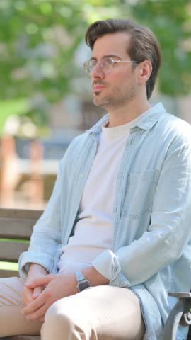 Casual Young Man with Migraine Sitting in Park