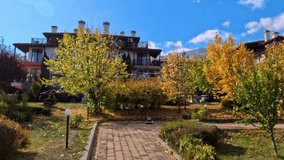 Sofia, Bulgaria - 19.10.2025. Autumn alley in a residential area with cobblestone path, yellow and red trees, and clear blue sky. Peaceful cityscape with warm seasonal colors and soft sunlight. - Powered by Shutterstock - Get 15% off with code: PIKWIZARD15