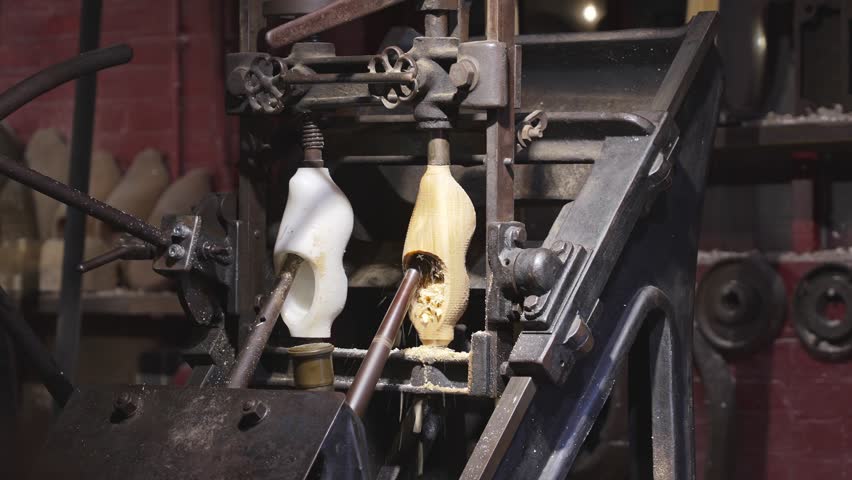 Industrial copy lathe shaping a wooden clog from raw block by following plastic mold with rotating cutters, traditional Dutch shoes