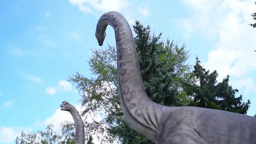Two large dinosaur figures in the park in summer.