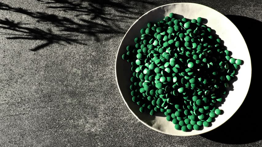 Green spirulina tablets plate. Algae supplements. Superfood. Natural source of iodine. 4k footage