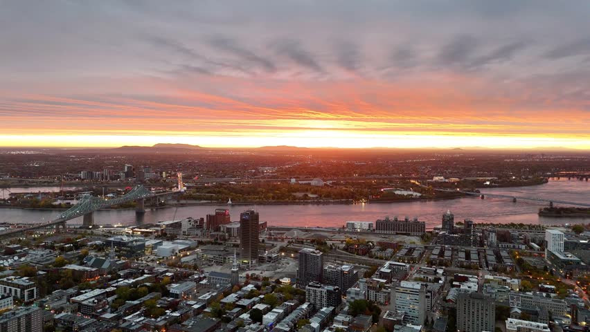 Vibrant sunset over Montreal skyline with St Lawrence River and La Grande Roue reflecting colorful evening sky. g.