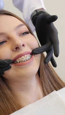Expert dentist finetunes dental braces, clinic professional carefully calibrates archwire