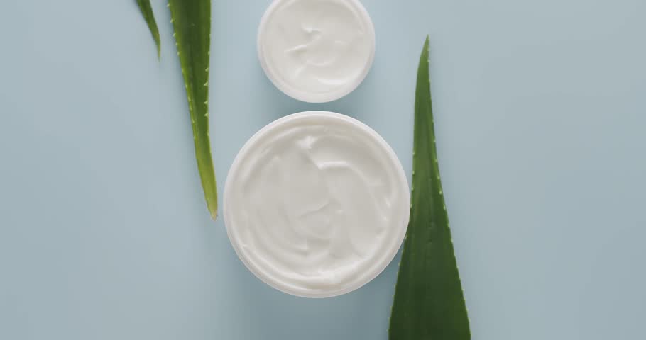 Cosmetics oils based on natural ingredients, scrub. cosmetic bottles. Jars, bottles and tubes with aloe vera plant for cosmetics and Beauty treatment spin on a light blue background. Top view.