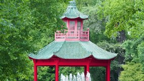 Camera slowly zooms on red pagoda, green tiled roof, lush garden, daylight, tranquil mood - Powered by Shutterstock - Get 15% off with code: PIKWIZARD15