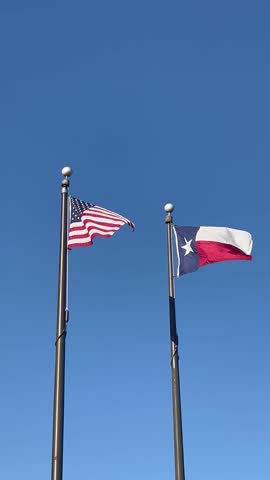 View of Texas and United States flags next to each other in air