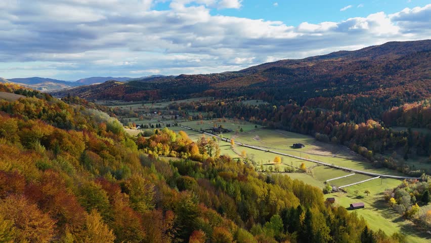 Drone footage showing a colorful valley surrounded by autumn forests and hills in Bucovina, Romania