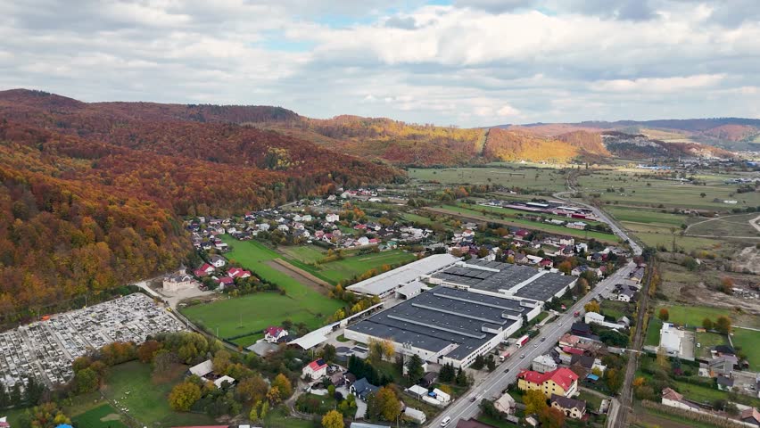 Drone footage over Gura Humorului showing Filatura industrial building surrounded by autumn hills in Bucovina, Romania