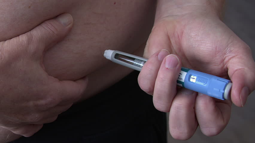 Close up man injects medication into subcutaneous abdomen with drug pen