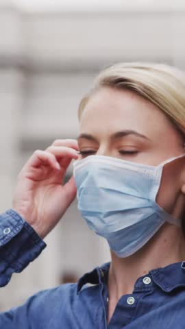 Animation of virus cells over caucasian woman wearing face mask. Global pandemic, healthcare, science and digital interface concept digitally generated video.