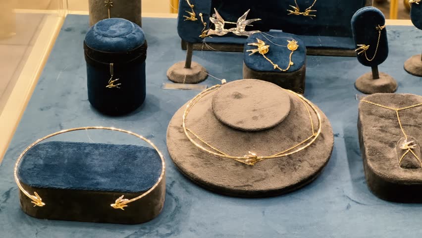 Luxury Jewelry Display: Gold Necklaces, Bracelets and Earrings on Velvet Stands | Elegant Boutique Window with Bird and Floral Motif Accessories | Fine Jewelry Store Interior Showcase