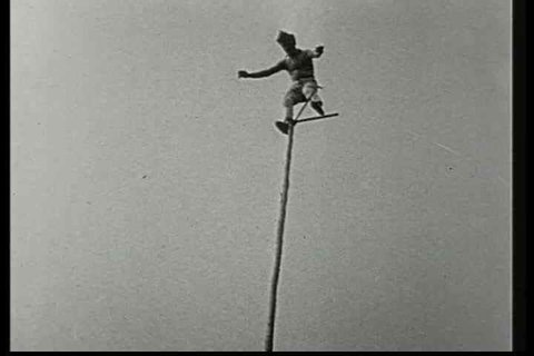 1920s - A man balances on a pole at a great height in this 1928 stunt film.