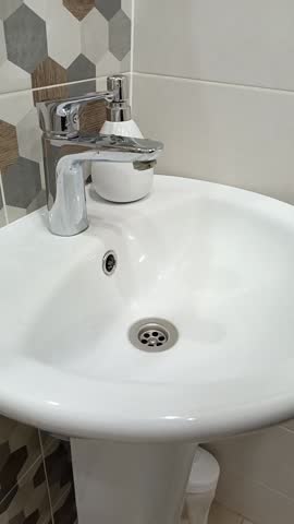 A woman turns on the tap and washes her hands in the bathroom. Hand hygiene, infection prevention