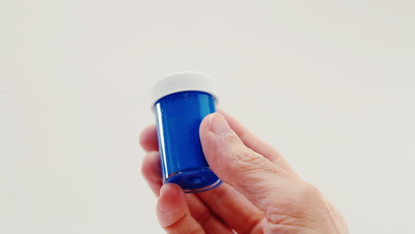 Close-up framing of hand holding and turning a blue acrylic tempera container