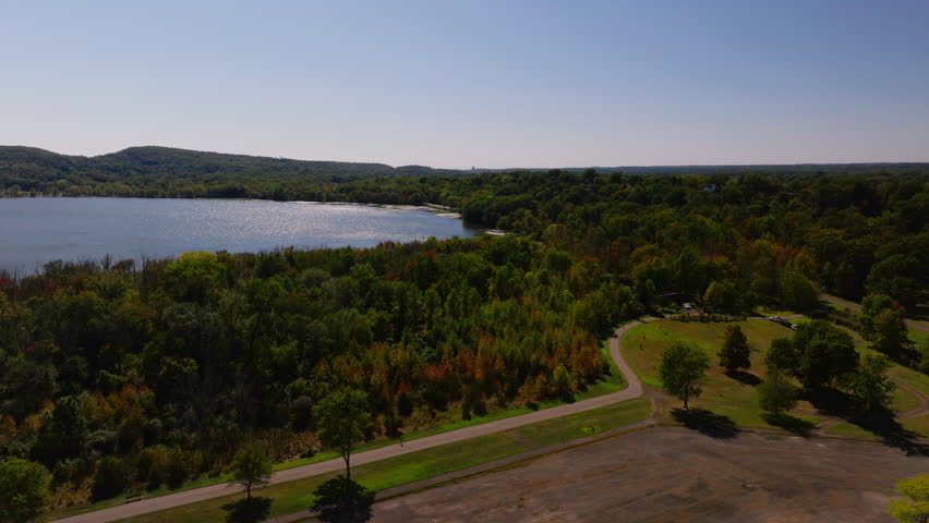 Aerial view of Rockland Lake surrounded by green and autumn trees with patches of water lilies near the shoreline, Rockland County, New York. ProRes HQ422.