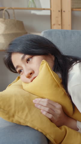 Vertical Screen : Young asian woman lay down on comfortable sofa in living room sleep after hard time work day and feel sick and bad, tired female fall asleep on couch at home, take nap or daydream.