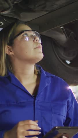 Animation of glowing light over woman working in car workshop. Small business, finance, computing and data processing concept digitally generated video.
