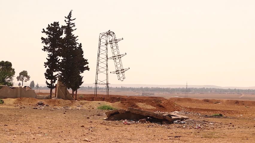 Destroyed electricity tower in a deserted Syrian landscape after years of conflict. Damaged infrastructure and barren land highlight the long-term impact on essential power systems. For crisis reports