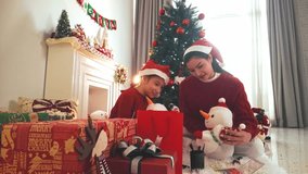 Cozy holiday morning in a bright living room as a parent and child in Santa hats open Christmas presents by a decorated tree and fireplace with stockings, garlands, and warm winter light. - Powered by Shutterstock - Get 15% off with code: PIKWIZARD15