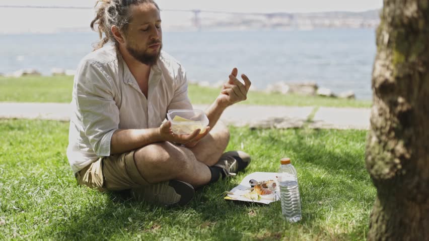 Man with dreadlocks eating healthy lunch in park