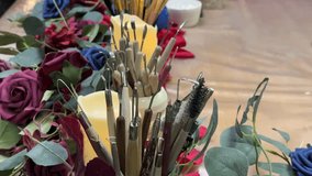 A festive, cozy close-up video clip of a creative work surface decorated with holiday or seasonal crafting supplies. The focus is on two flickering LED pillar candles and two decorative ceramic pots - Powered by Shutterstock - Get 15% off with code: PIKWIZARD15