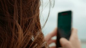 Close up of unrecognizable woman holding smartphone while filming sea from ferry in Dunkirk port France. Wind blowing hair during mobile video capture on ocean ride near harbor. Person recording - Powered by Shutterstock - Get 15% off with code: PIKWIZARD15