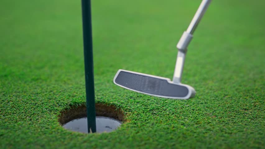 Close-up of putter making contact with golf ball near the hole on a vibrant green golf course. Perfect for sports enthusiasts looking for dynamic leisure visuals. - Powered by Shutterstock - Get 15% off with code: PIKWIZARD15
