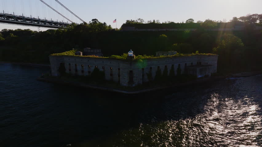 Close-up aerial view of Battery Weed historic fort in Staten Island, New York, showing detailed stone walls, arched passages, and greenery on top under clear blue sky. ProRes HQ422.