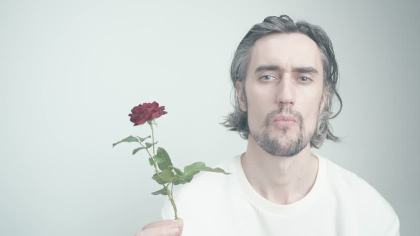 Arrogant Young Man Holding a Rose in Soft Lighting, Expressive Gestures, and Contemplative Atmosphere, Emotional Connection