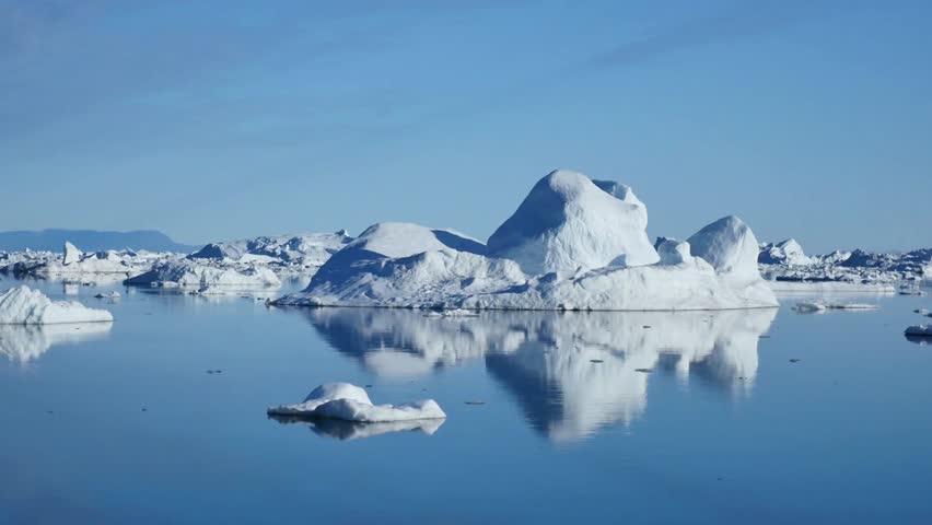 Icebergs float serenely in the arctic waters under a clear blue sky reflecting beauty