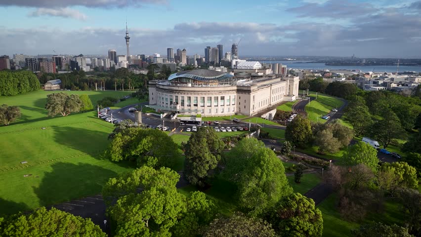 Aerial view of the Auckland War Memorial Museum surrounded by lush green grass, with the city skyline in the distance, Auckland, Auckland, New Zealand.