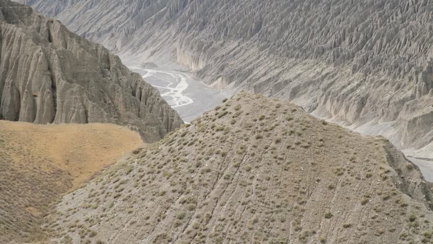 Dramatic canyon landscape with steep cliffs and a winding river under a cloudy sky