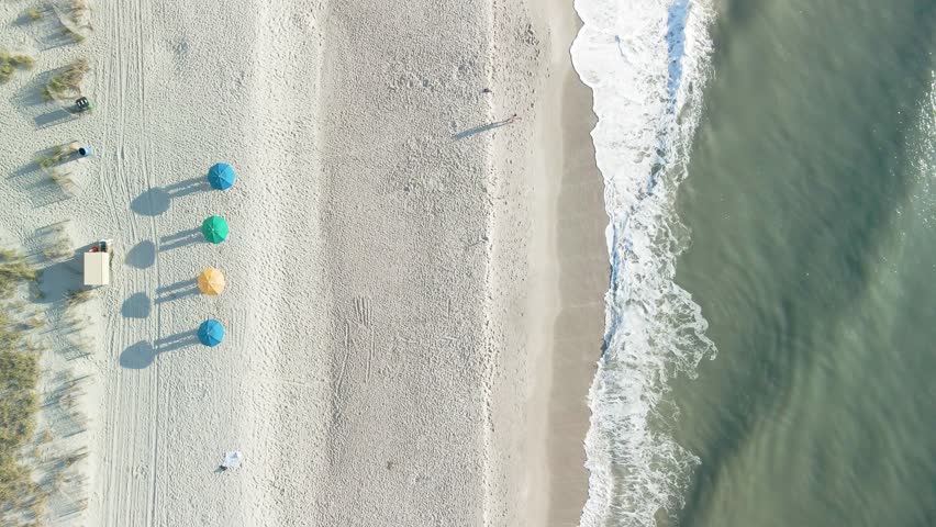 Aerial top-down hovering above Myrtle Beach, South Carolina, with umbrellas and people walking